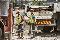 workers drilling borehole near processing plant