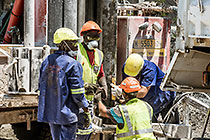 workers drilling borehole near processing plant