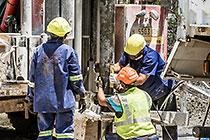 workers drilling borehole near processing plant