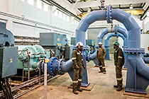 workers checking pump & pipes in pumping building