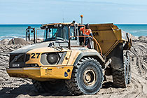 drivver standing on truck used to carry sand for beach nourishment