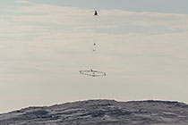helicopter flying with SkyTEM rig over arid plain