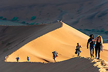 people hiking on sand dune ridge