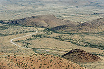 road through plain & mountains covered with dry grass
