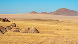 track near granite boulders in grassy plain