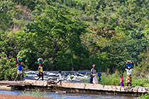 women & children crossing brocken bridge over river