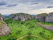 sandy track through huge granite boulders between green vegetation