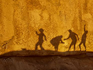 people shadows on granite boulder at sunset