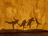 people shadows on granite boulder at sunset