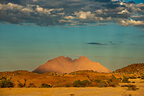 small spitzkoppe mountain under clouds at sunset