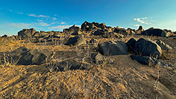 rocks & dry grass on hill at sunset