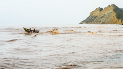 2 boys in small boat struggling to get over waves