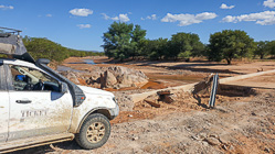 ranger camper in front of damaged bridge by strong river