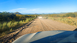 camping cars driving on gravel road through green bushes