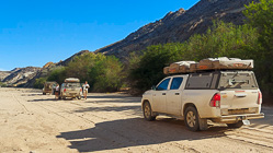 Julien & Manon near camping cars & ranger camper in snady riverbed