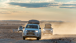 camping cars driving on rocky plain at sunset
