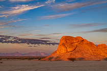 red granite rock under clouds at sunset